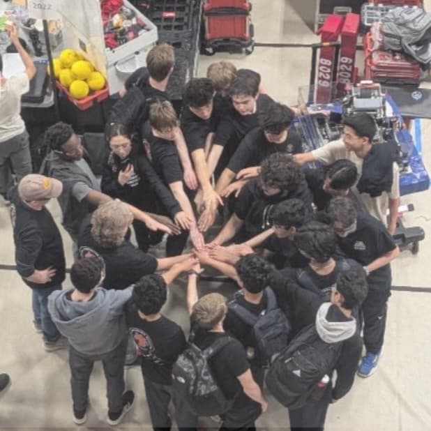 The team gathered in a circle in the pit, every hand reaching into the centre