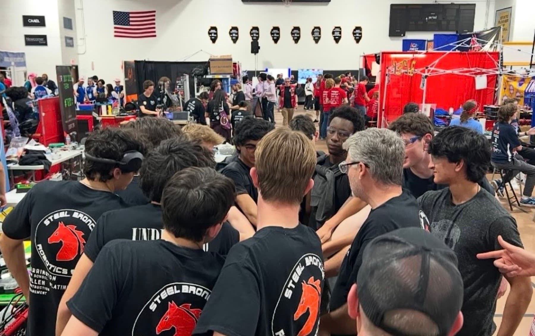 The team huddled together in the pit, hands in the center, before a match