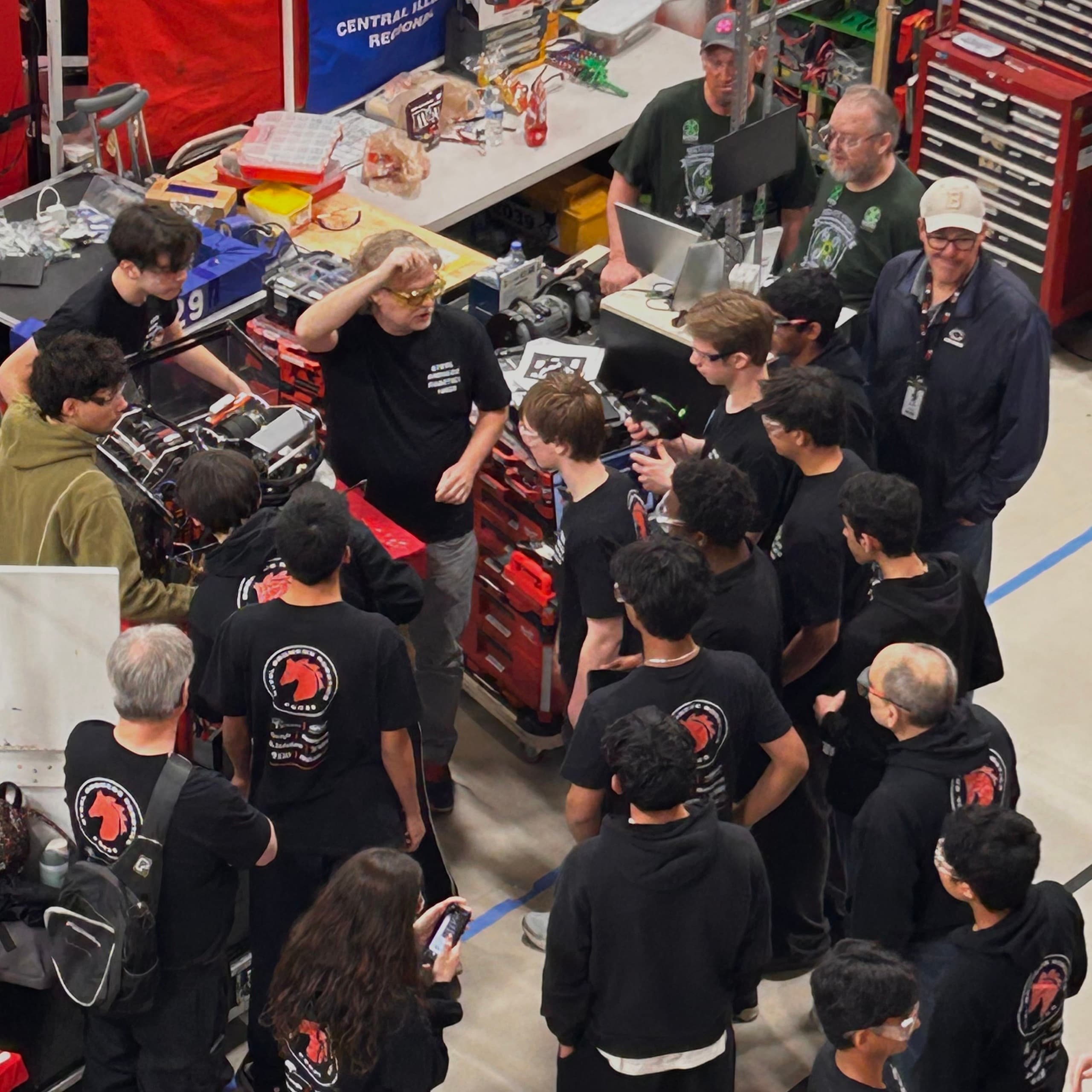 The team and its mentors gathered around the robot in the pit at a regional competition